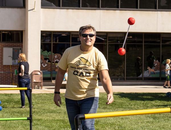 Man throwing a ladder ball wearing a t-shirt that says Prairie Wolf Dad